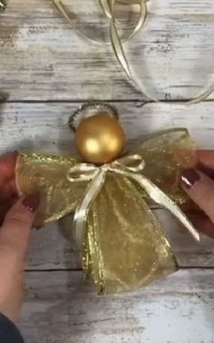 someone is holding a gold ornament on top of a piece of fabric with a bow