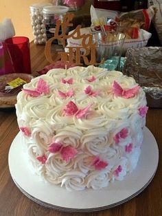 a cake with white frosting and pink flowers on top is sitting on a table