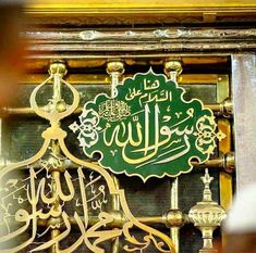 an ornate sign with arabic writing in gold and green on the front of a building