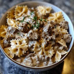 a bowl filled with pasta and meat in gravy on top of a table