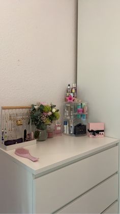 a white dresser topped with lots of drawers and vases filled with different types of flowers