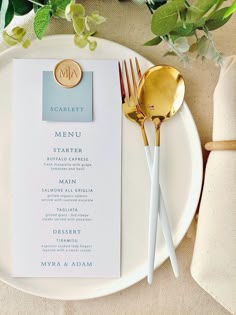 a white plate topped with a menu and gold utensils