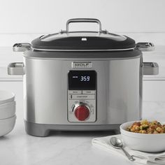 a slow cooker sitting on top of a counter next to a bowl of food