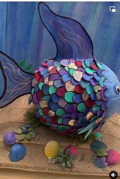 a blue fish with multicolored scales on it's body and some sea shells around it