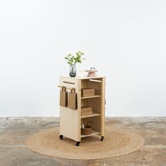 a small wooden cart with drawers and flowers in it on top of a round rug