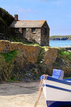 a boat sitting on top of a sandy beach next to a stone wall and building