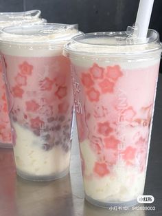 two cups with pink and white toppings are on the table next to each other