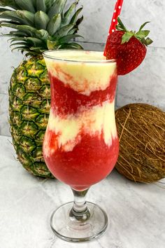 a red and white drink in a glass next to a pineapple