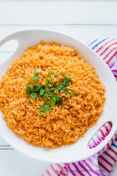 mexican rice in a white bowl with cilantro and parsley on the side