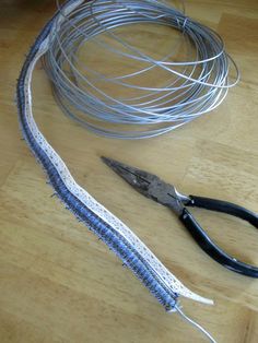 a pair of scissors sitting on top of a wooden table next to wires and wire