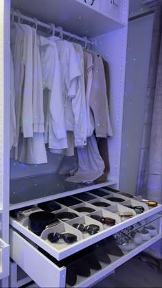 an organized closet with shoes and shirts hanging on the rack in front of it is lit by blue lights