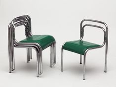 two green chairs sitting next to each other on top of a white surface with metal legs