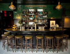 a bar with stools and bottles on the wall