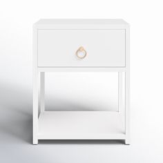 a white bedside table with a gold ring on the front and bottom drawer, against a gray background