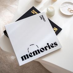 two magazines sitting on top of a white table next to candles and other items in the background