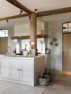 a kitchen with white cabinets and wooden beams in the ceiling, along with an island