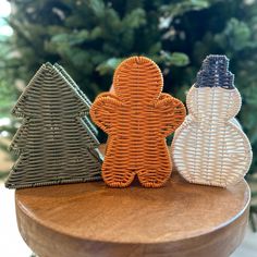 three woven christmas trees sitting on top of a wooden table next to a pine tree