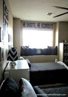 a bedroom with two beds and a ceiling fan in the corner, next to a window that says he shoots, he scores