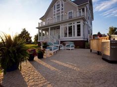 an outdoor patio with chairs and grill in front of a large house