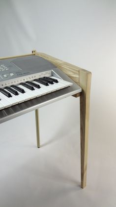 an electronic keyboard sitting on top of a wooden table next to a white wall with black keys