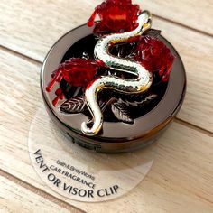 a compact case with a snake and roses on the front, sitting on a wooden surface