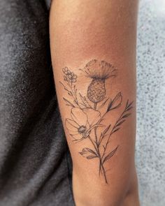 a woman with a tattoo on her arm holding onto a flower and leaves design in black ink