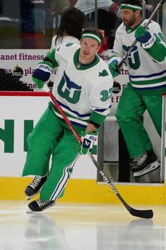 two men in green and white uniforms playing hockey