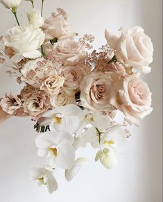 a woman holding a bouquet of flowers in her hand with white and pink roses on it