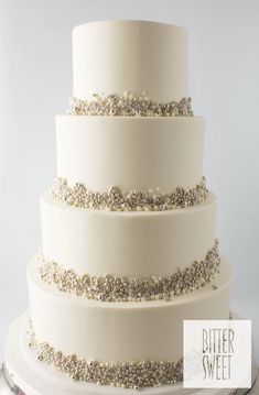 a white three tiered cake with silver glitters