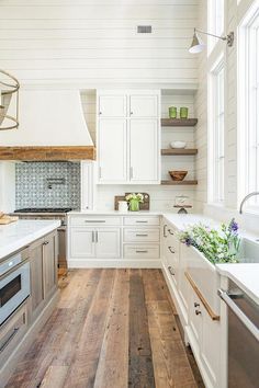 a kitchen with white cabinets and wood floors