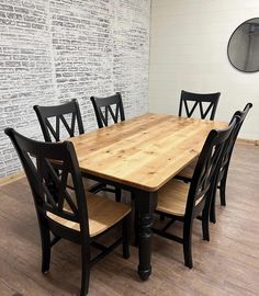 a dining room table with six chairs and a brick wall in the backround