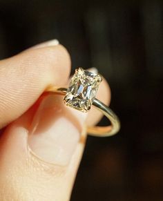 a person holding a ring with a diamond in it's middle finger and gold band