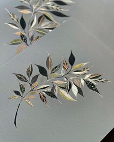 two sheets of paper with leaves painted on them, one is silver and the other is gold