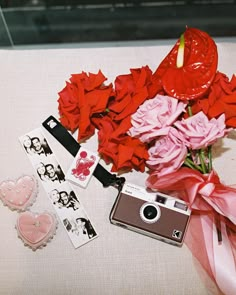 a bouquet of roses and some stickers on a white table with a pink ribbon