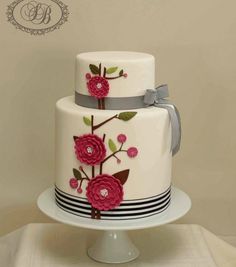 a three tiered cake decorated with flowers and ribbons on a white plate, sitting on a table