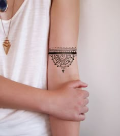 a woman's arm with a black and white tattoo design on the left wrist