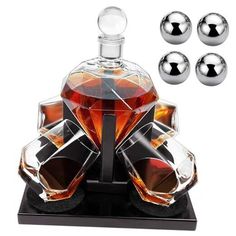 three glass bottles and four chrome balls on a black stand with one bottle in the middle