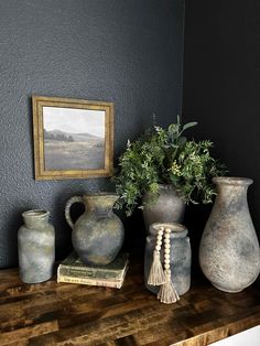 three vases are sitting on a table next to a painting and a framed picture