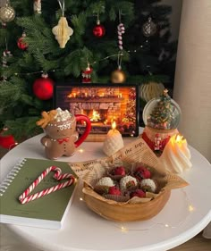 a table topped with a basket filled with candy and cookies next to a christmas tree