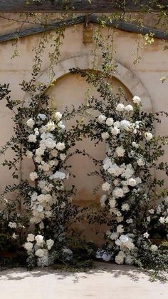 an arch with white flowers and greenery on it