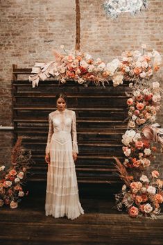 a woman standing in front of a floral arch