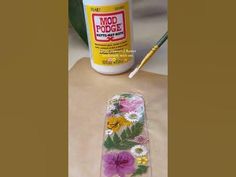 a bottle of glue sitting on top of a wooden table next to flowers and leaves