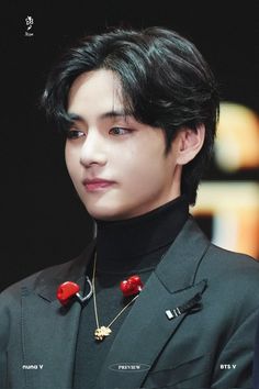 the young man is wearing a black suit and red necklace