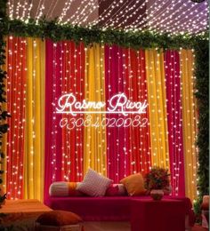 a red couch sitting in front of a curtain covered wall with white lights on it