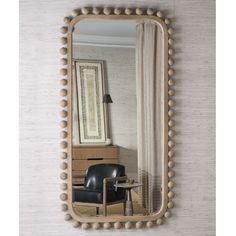 a mirror that is hanging on the wall next to a chair and table with a lamp