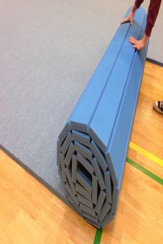 a person standing on top of a blue mat in the middle of a gym floor