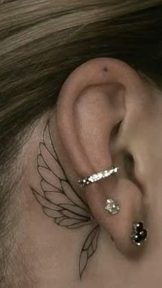 a woman with ear piercings on her ears and behind the ear is an angel wing