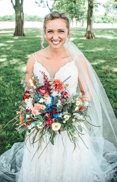 a woman in a wedding dress is holding a bridal bouquet and smiling at the camera