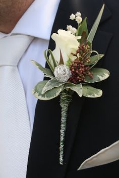 a boutonniere with white flowers and greenery is worn by a man in a suit