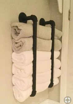 towels are hanging on the wall in a bathroom with two black towel racks and one white towel rack